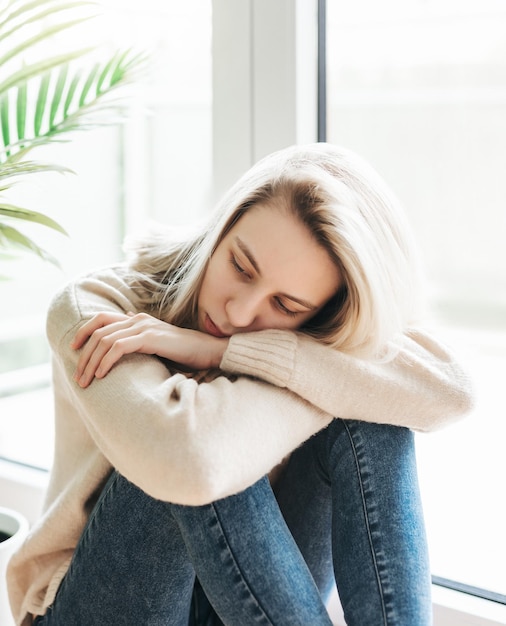 Menina triste perto da janela pensando em algo