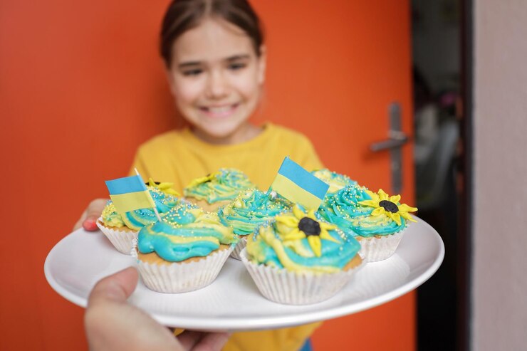 Foto menina ucraniana para quem os vizinhos trouxeram cupcakes com creme em cores amarelas e azuis para o brunch