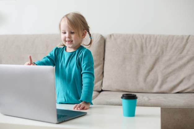 Menina usa um bate-papo por vídeo de laptop para comunicar o aprendizado em casa criança estudando on-line