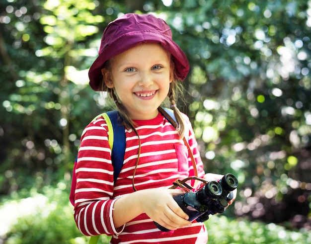 Menina usando binóculos na floresta