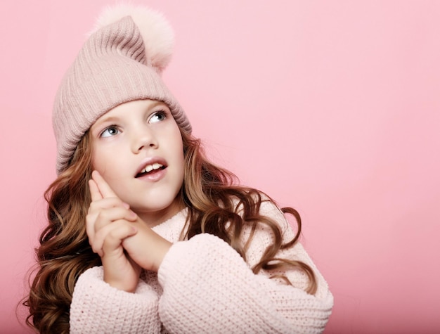 Menina usando chapéu de inverno rosa e suéter sobre fundo rosa fechar