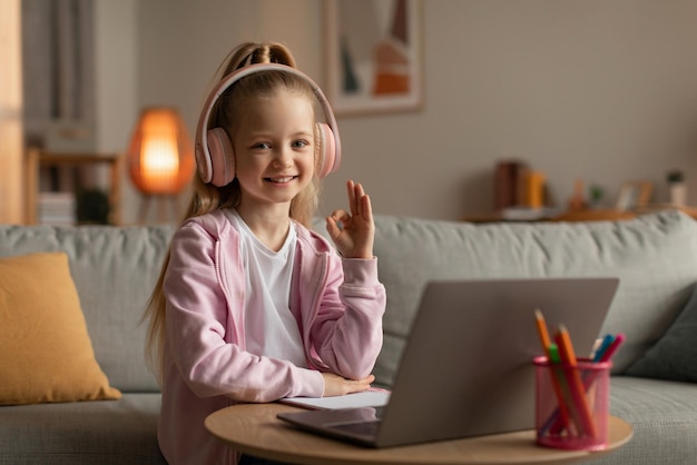 Menina usando laptop gesticulando bem aprendendo online em casa