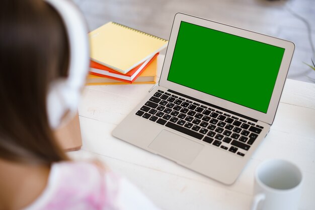 Menina usando laptop para fazer o dever de casa em casa