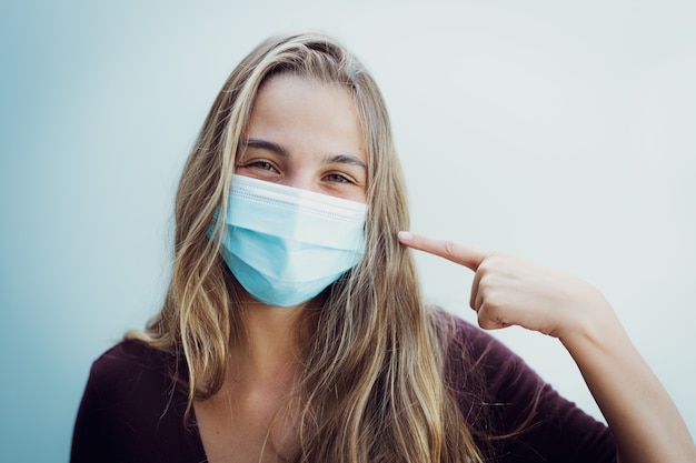 Menina usando máscara devido ao coronavírus e sorri conceito positivo