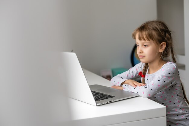 Menina usando o bate-papo por vídeo no laptop em casa. Espaço para texto