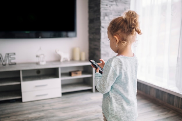 Menina usando o controle remoto da TV