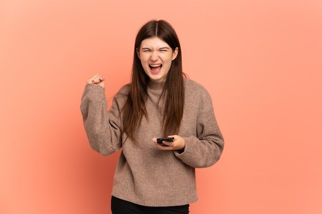 Menina usando telefone celular e fazendo gesto de vitória