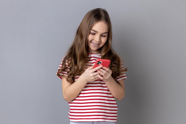 Menina usando telefone inteligente olhando para a tela do dispositivo escrevendo post para o blog de seu filho