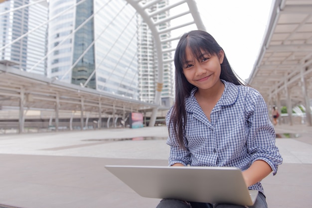 Menina usando um dispositivo macbook com uma cidade grande e moderna