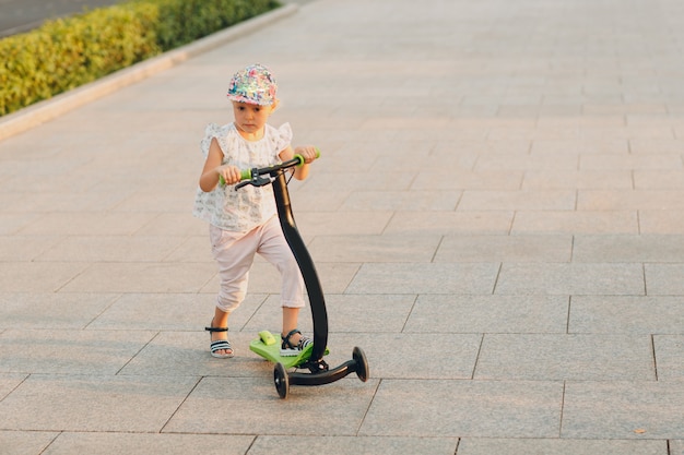 Menina usando uma scooter na rua da cidade.