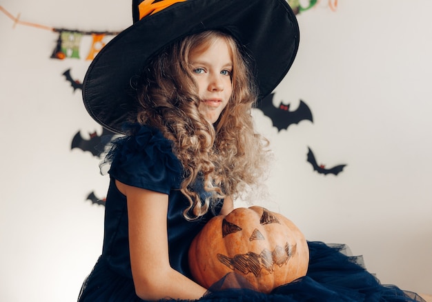 Menina vestida de bruxa com uma abóbora. dia das Bruxas. abóbora para o halloween