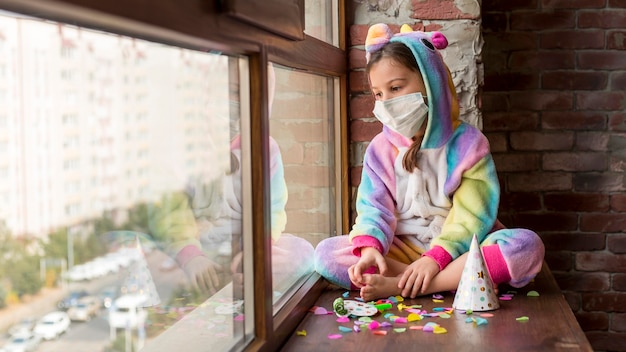 Foto menina vestida de dinossauro em casa com máscara facial