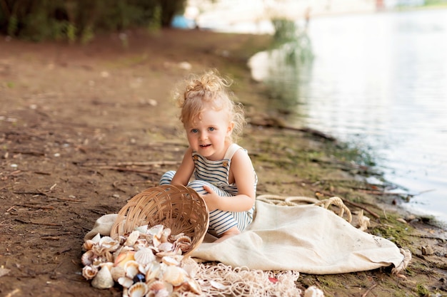 Menina vestida de marinheiro em uma praia com conchas à beira-mar