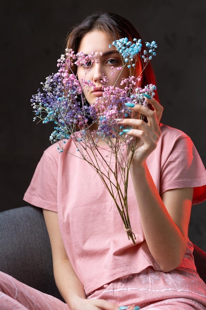 Menina vestida de pijama rosa segurando um buquê de flores secas