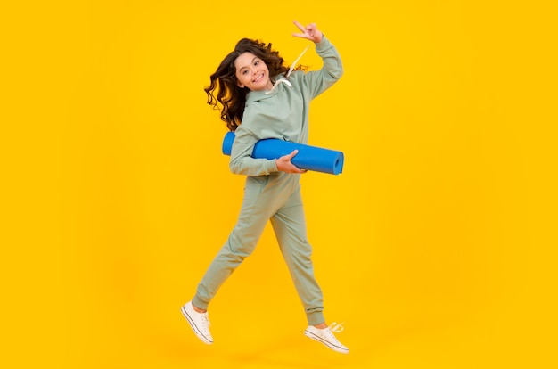 Menina vestida de uniforme esportivo correr e pular criança em um terno esportivo elegante e elegante em um capuz