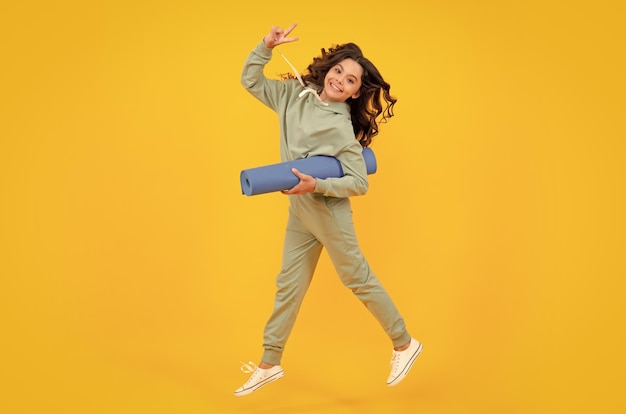 Foto menina vestida de uniforme esportivo correr e pular criança em um terno esportivo elegante e elegante em um capuz