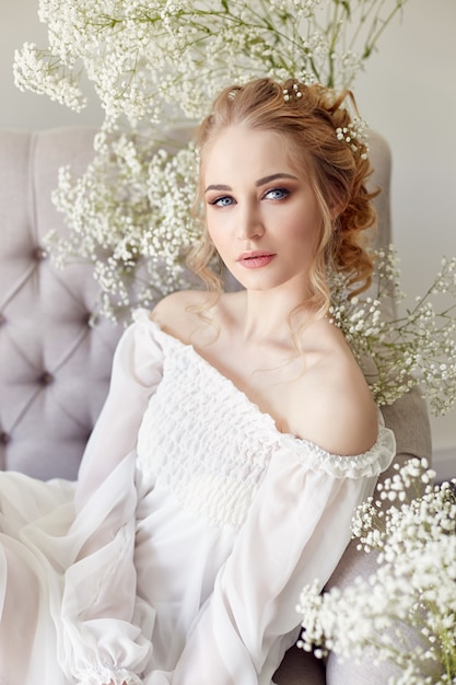 Menina vestido de luz branca e cabelos cacheados, retrato de mulher com flores em casa