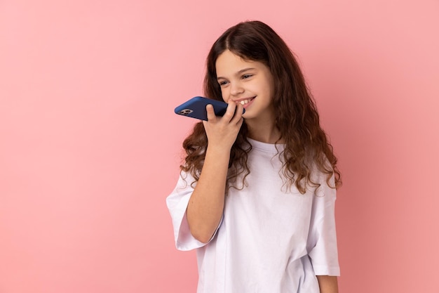 Menina vestindo camiseta branca falando com smartphone usando o aplicativo de alto-falante digital de assistente virtual