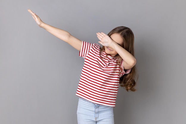 Menina vestindo camiseta listrada mostrando a pose de dança dab famoso meme da internet