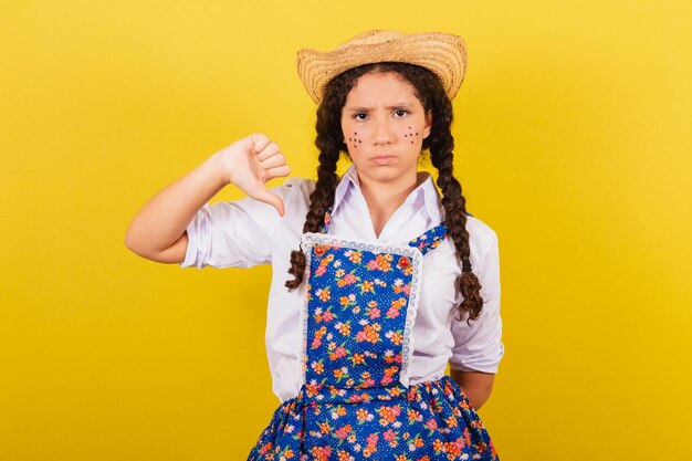 Menina vestindo roupas típicas para a Festa Junina polegar para baixo desaprovação negativa para a festa Arraia