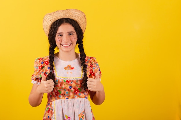 Menina vestindo roupas tradicionais de laranja para festa junina Polegar para cima aprovação afirmativa
