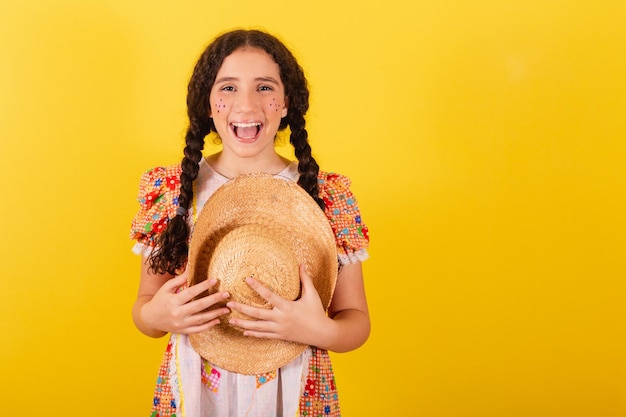 Menina vestindo roupas tradicionais de laranja para festa junina Saudando e sorrindo usando chapéu