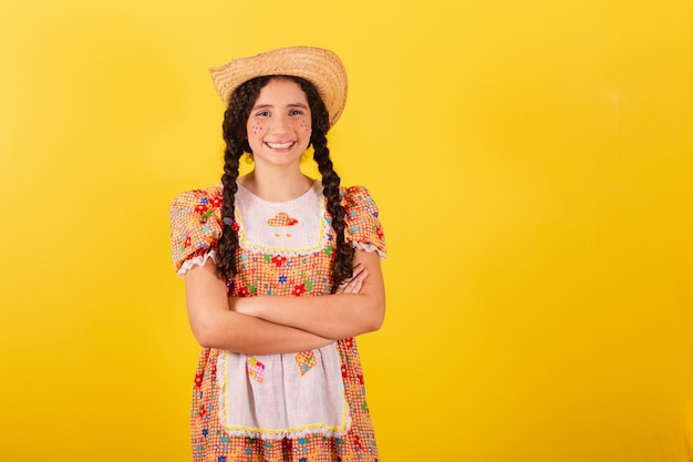 Menina vestindo roupas tradicionais laranja para festa junina Braços cruzados sorrindo