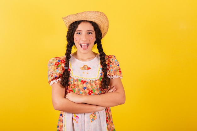 Menina vestindo roupas tradicionais laranja para festa junina Braços cruzados sorrindo