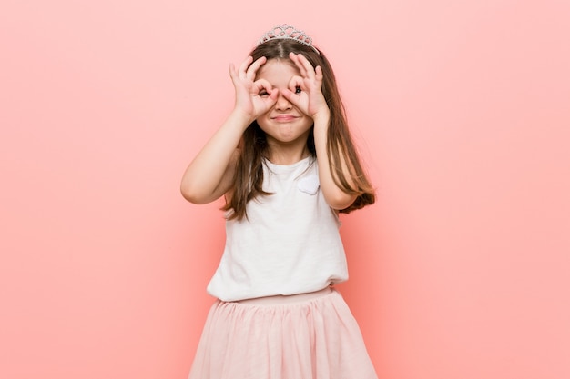 Menina vestindo um olhar de princesa mostrando sinal bem sobre os olhos