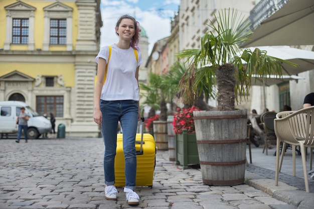 Menina viajante andando com mochila e mala amarela