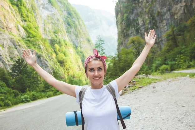 Menina viajante nas montanhas acenando e rindo