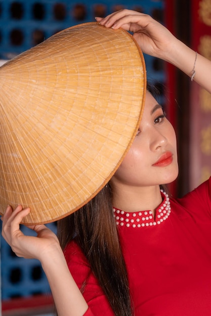 Menina vietnamita com vestido Ao Dai de pé na casa tradicional do Vietnã O texto na foto significa melhores desejos de felicidade familiar, prosperidade, saúde, feriado de Tet e Ano Novo