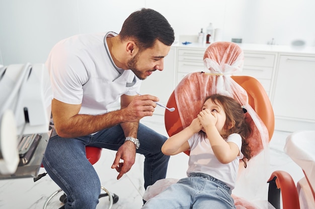 Menina visitando dentista masculino na clínica Concepção de estomatologia