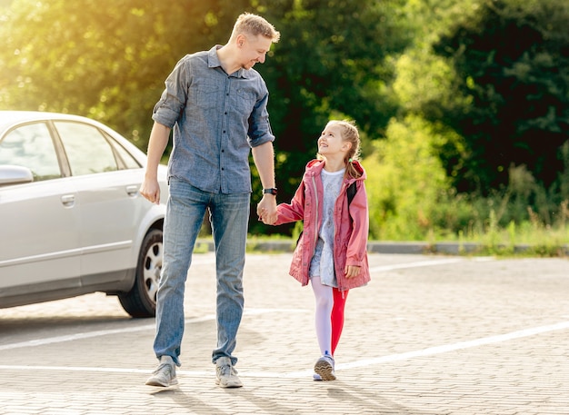 Menina voltando para a escola de mãos dadas com o pai