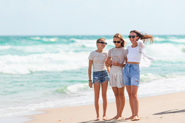 Foto meninas adoráveis e jovens mães na praia branca tropical