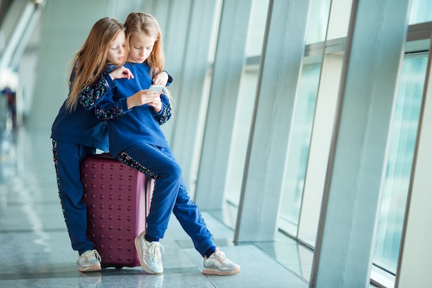 Meninas adoráveis no aeroporto perto da grande janela