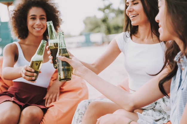 Meninas africanas clinks garrafa de cerveja na festa de praia.