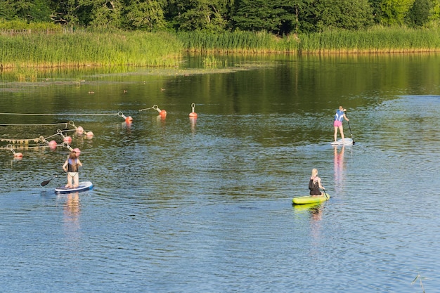 Meninas andam de prancha no rio Pirita no verão Foto de alta qualidade