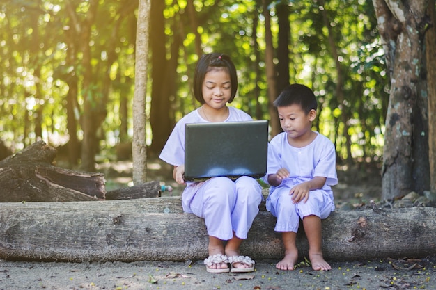 Meninas asiáticas e menino usando o notebook de procurar alguma informação na zona rural da Tailândia