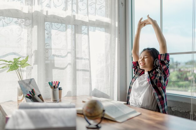 Meninas asiáticas estão felizes estudando online em casa. Usar laptops e fones de ouvido como ferramentas para ajudar no aprendizado online.