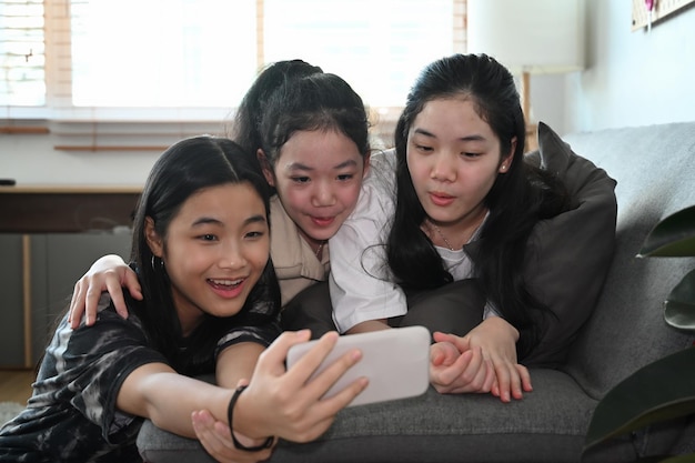 Meninas asiáticas felizes tomando selfie com smartphone inteligente em casa