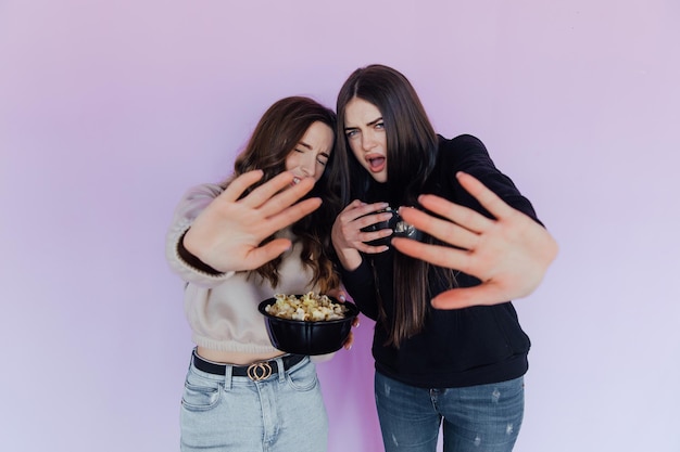 Foto meninas assustadas e chocadas, amigas assistindo filme, seguram balde de pipoca