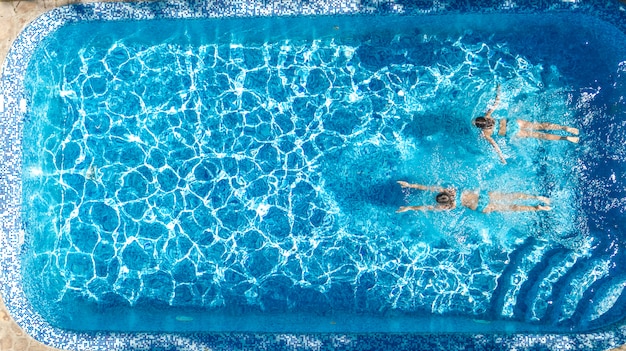 Meninas ativas na piscina água zangão aéreo vista de cima, crianças nadam, crianças se divertem em férias em família tropical, conceito de resort de férias