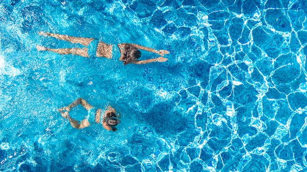 Meninas ativas na piscina água zangão aéreo vista de cima, crianças nadam, crianças se divertem em férias em família tropical, conceito de resort de férias