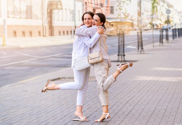 Meninas bem vestidas fascinantes gostando de se encontrar Foto ao ar livre de senhoras bonitas se abraçando no fundo da rua