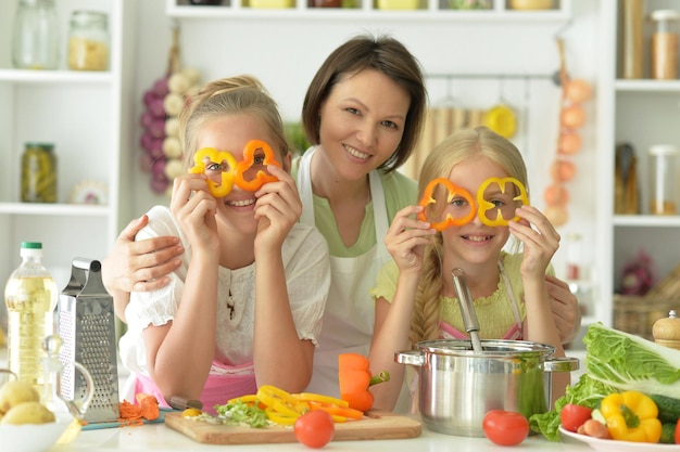 Meninas bonitas com a mãe a cozinhar na cozinha.