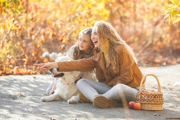 Meninas bonitas com retriever dourado. duas irmãs que têm ao ar livre proprietários de fun.pet no outono.