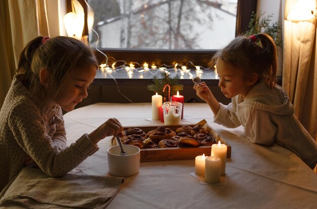 Meninas bonitas estão cozinhando pão de gengibre de Natal em uma mesa de madeira Preparação de passatempo familiar para as férias de Natal