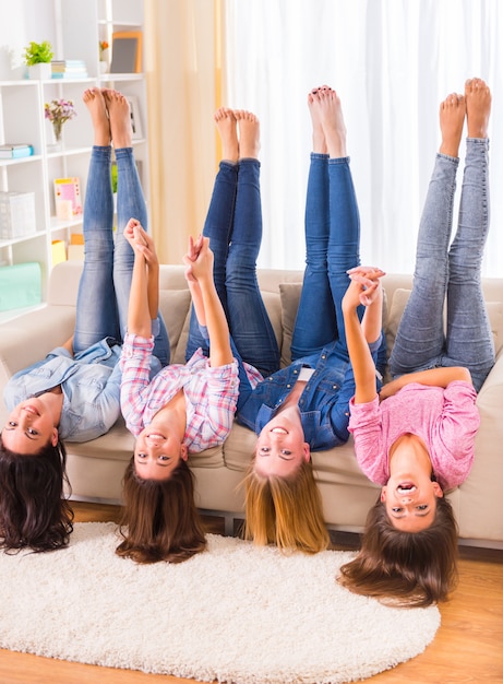 Meninas bonitas que encontram-se no sofá em casa e sorriso.