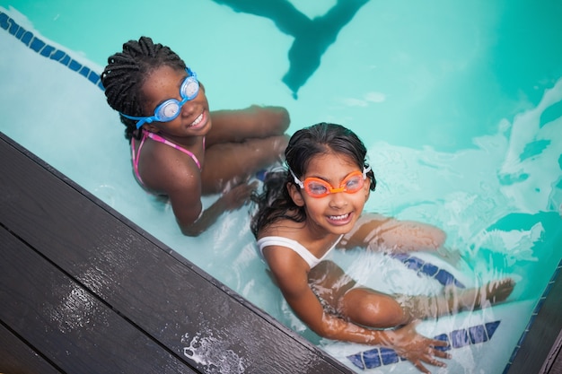 Meninas bonitas sentadas ao lado da piscina